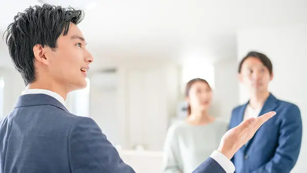 若い夫婦がダイニングテーブルでスーツの男性とノートパソコンを使いながら相談しているシーン