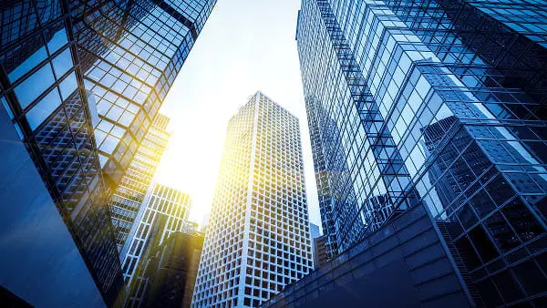 スーツ姿の担当者と向かい合い、書類にサインをする中年夫婦の様子を捉えた場面